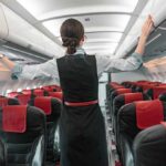Flight attendant checks overhead bins in empty airplane cabin