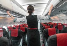 Flight attendant checks overhead bins in empty airplane cabin