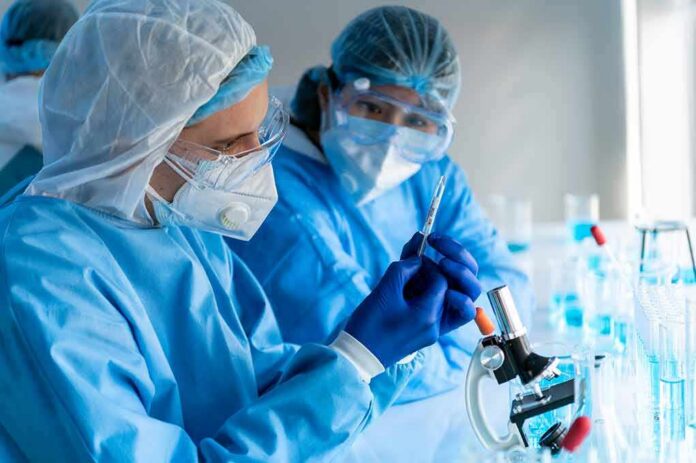 shutterstock_1723539451 Scientists in protective gear working with a syringe in a laboratory