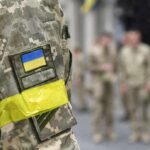 Soldier in camouflage with Ukrainian flag patch and yellow armband