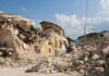 Rubble from collapsed buildings in earthquake-hit area. Clear sky.