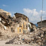 Rubble from collapsed buildings in earthquake-hit area. Clear sky.