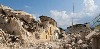 Rubble from collapsed buildings in earthquake-hit area. Clear sky.