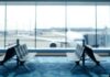 Blurred view of an airport terminal with seats and an airplane in the background