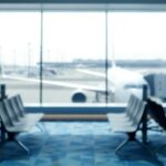 Blurred view of an airport terminal with seats and an airplane in the background