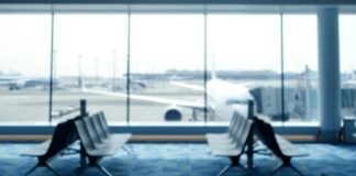 Blurred view of an airport terminal with seats and an airplane in the background
