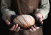 Person holding a freshly baked loaf of bread in a cloth