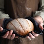 Person holding a freshly baked loaf of bread in a cloth
