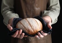 Person holding a freshly baked loaf of bread in a cloth