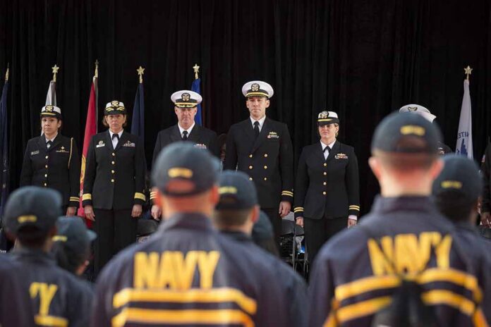 Navy officers stand at attention on stage during a ceremony