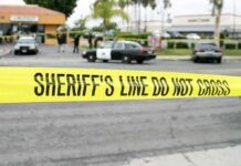 yellow sheriff's line tape blocks a street near police cars