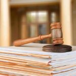 Authorities Charge Man in Catastrophic Wildfire judge's gavel resting on a stack of case files