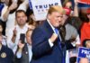 Sanctions Blitz Targets Shadow Fleet man in suit raising fists at a rally podium