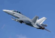 Twin-engine fighter jet climbing in a clear blue sky