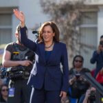 Why Critics Are Focused on Point Dume woman in navy suit waving at an outdoor event