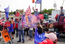 Follow The Money: MAGA’s Untouchable Network Crowd of people at a political rally holding flags and signs