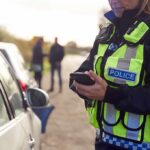 Police officer using a smartphone during a roadside stop