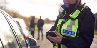 Police officer using a smartphone during a roadside stop