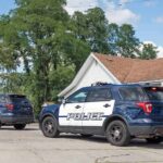 Two police SUVs parked near a suburban house