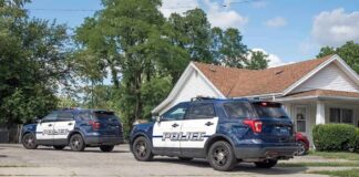 Two police SUVs parked near a suburban house