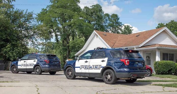 Two police SUVs parked near a suburban house