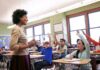 Teacher engaging with students raising hands in a classroom