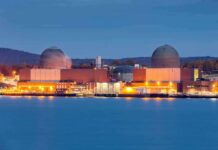 Nuclear Giant Kneels To A River nuclear power plant with two domed reactor buildings by water at dusk