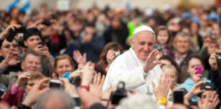 religious leader in white robes waving to a crowd