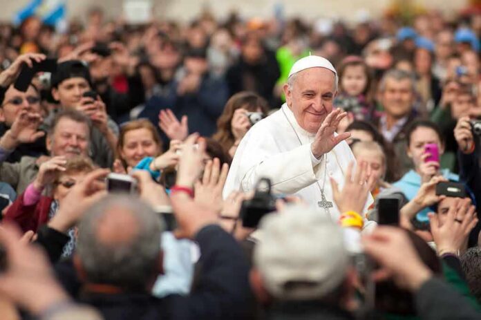 religious leader in white robes waving to a crowd
