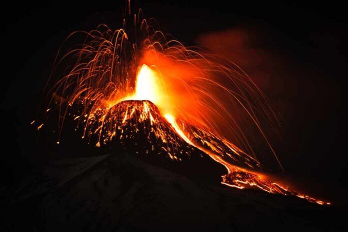shutterstock_641213743 Volcano erupting at night with glowing lava and ash plume
