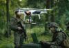quadcopter drone hovering near soldiers in a forest