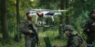quadcopter drone hovering near soldiers in a forest