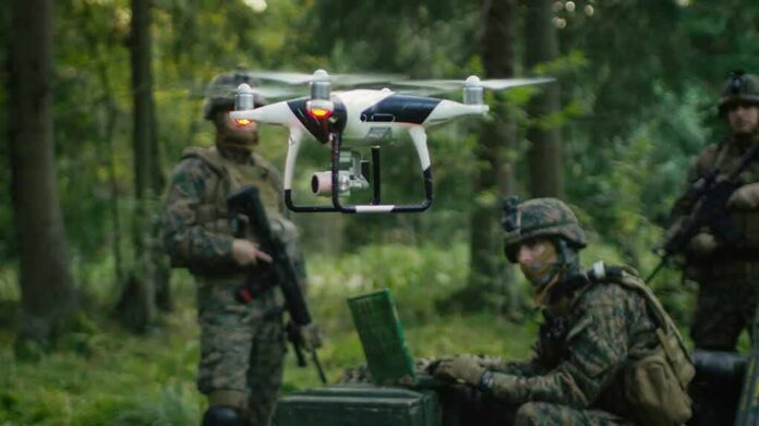shutterstock_761939488 quadcopter drone hovering near soldiers in a forest