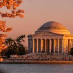 Jefferson Memorial at sunset with cherry blossoms and visitors by the water