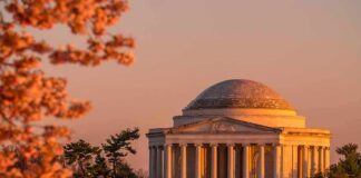 Jefferson Memorial at sunset with cherry blossoms and visitors by the water