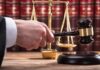 Judge's hand holding gavel near scales of justice