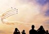 formation jets performing aerobatics above crowd