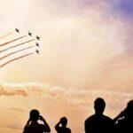 formation jets performing aerobatics above crowd