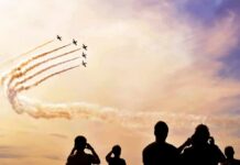 formation jets performing aerobatics above crowd