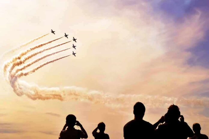 formation jets performing aerobatics above crowd