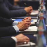 Navy Pilots May Face An Invisible Risk Hands of people in suits taking notes at a conference table