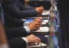Capitol Cash Grab Meets Surprise Roadblock Hands of people in suits taking notes at a conference table