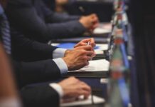 Capitol Cash Grab Meets Surprise Roadblock Hands of people in suits taking notes at a conference table