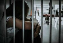 Person sitting behind jail bars with head down