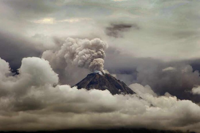 Volcano erupting with ash plume above cloud layer