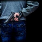 person holding a handgun behind their back