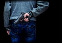 person holding a handgun behind their back