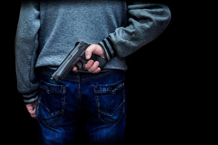 person holding a handgun behind their back