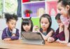 Children gathered around a tablet on a table