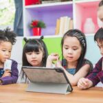 Children gathered around a tablet on a table